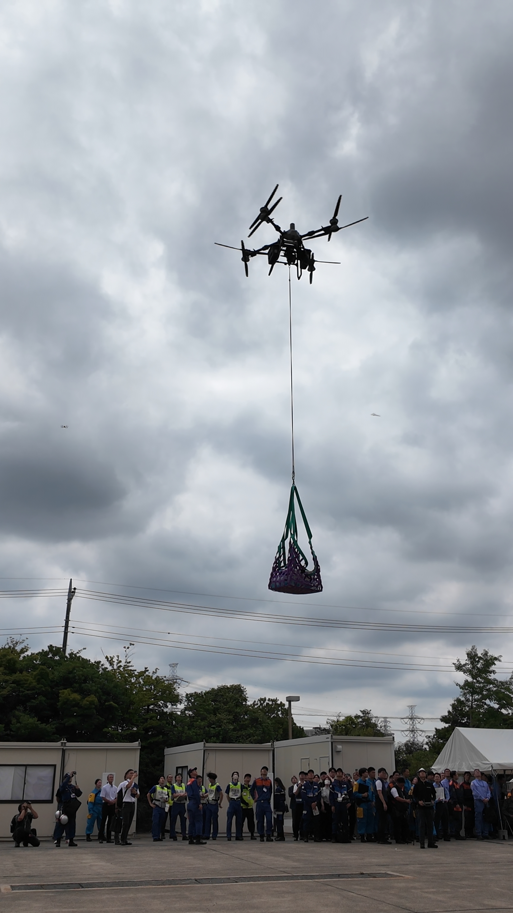 観衆の前で救援物資を吊り上げるFlyCart100