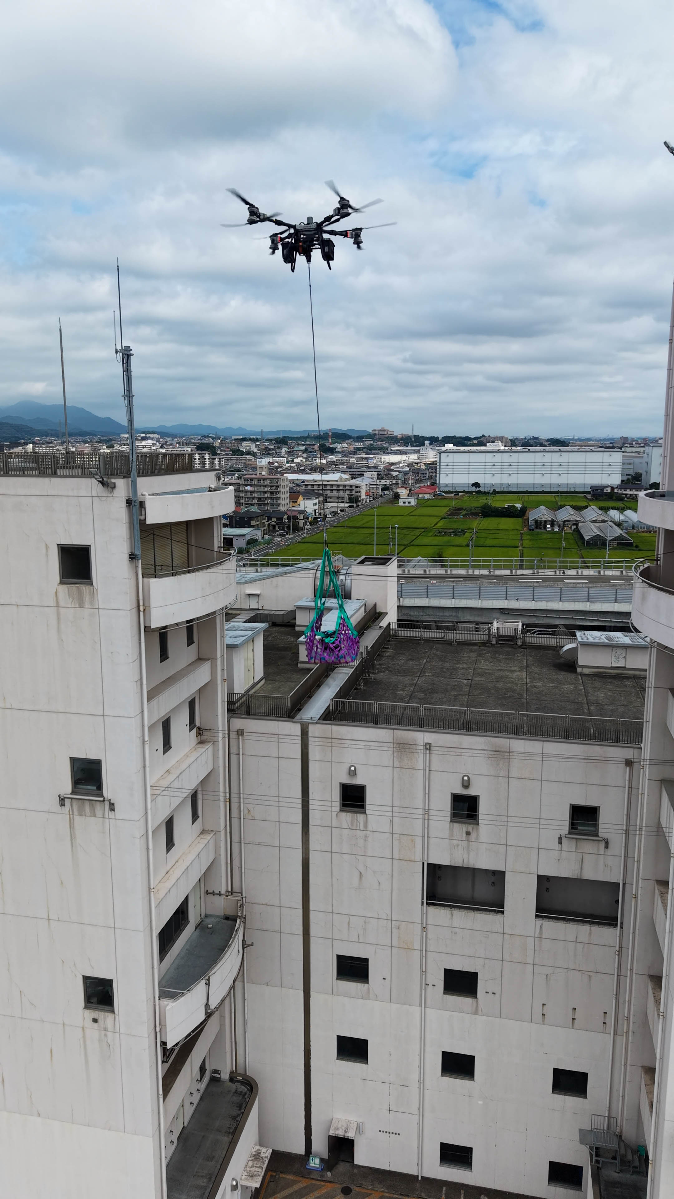 市街地上空で救援物資を吊り下げて飛行するFlyCart100